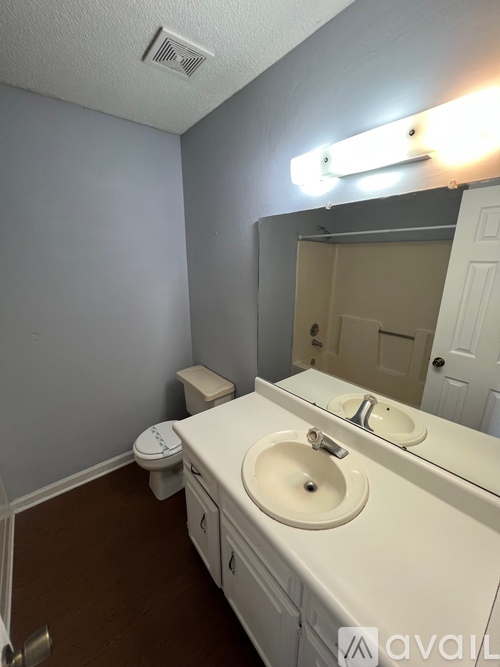 A bathroom with a toilet, sink, and mirror.