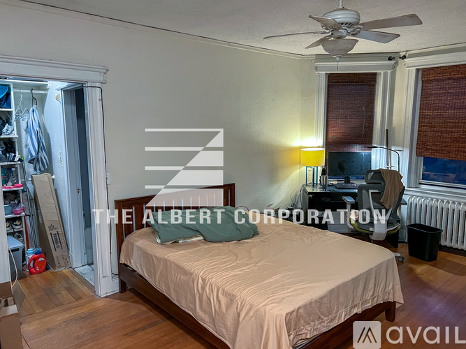 A bedroom with a bed, a ceiling fan, and a window with blinds.