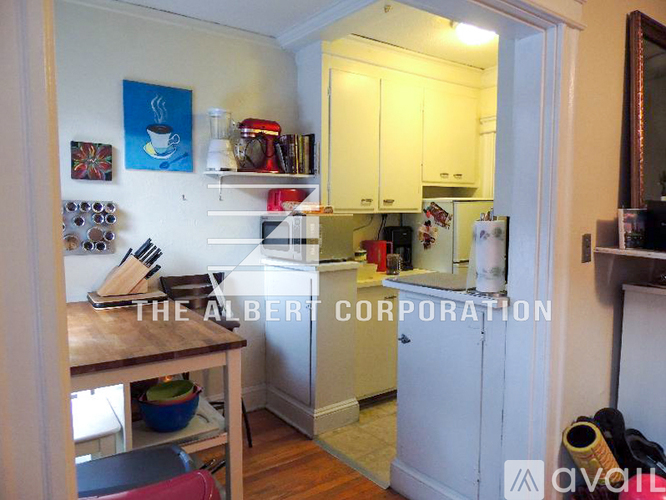 A kitchen with white cabinets and a refrigerator.
