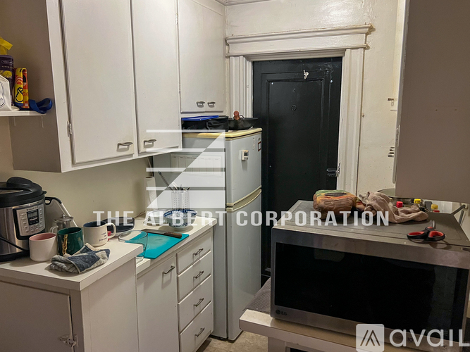 A kitchen with white cabinets and a black door.