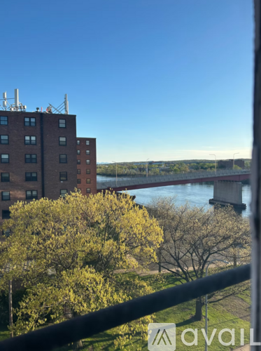 A view from a balcony overlooking a river with a bridge in the distance and buildings in the foreground.