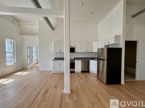 A spacious kitchen with white cabinets and a black refrigerator.