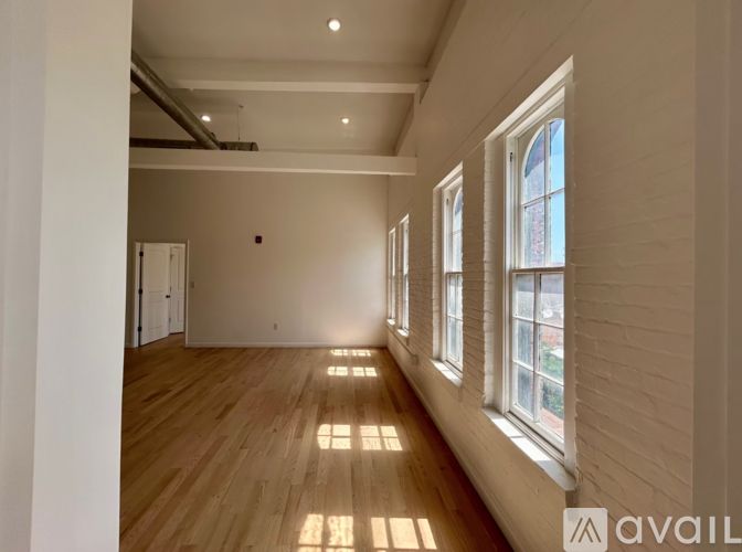 A long hallway with wooden floors and windows on the side.