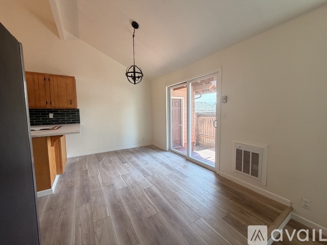 A spacious room with wooden flooring and a hanging light fixture.