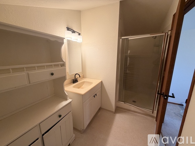 A bathroom with a sink, mirror, and shower.
