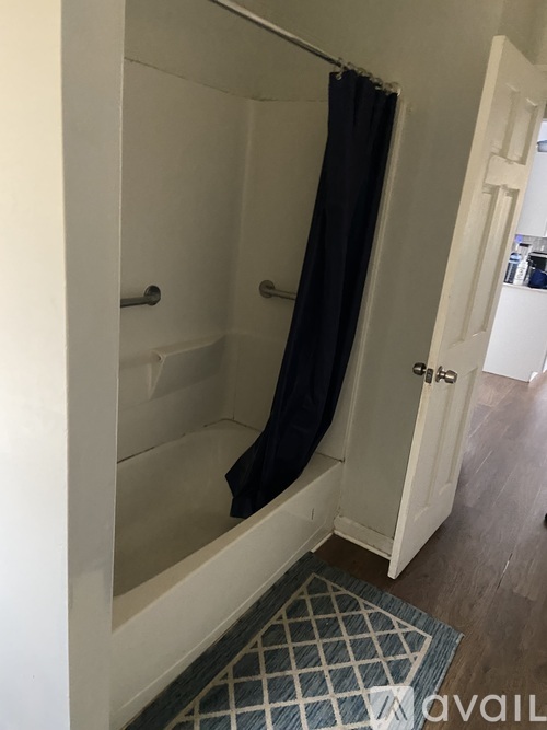 A bathroom with a white shower stall and a black shower curtain.
