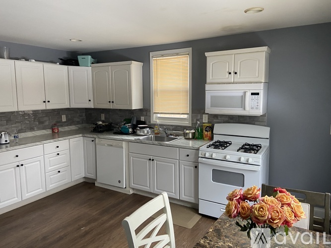 A kitchen with white cabinets and a white stove top oven.