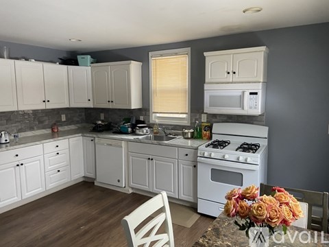 A kitchen with white cabinets and a white stove top oven.