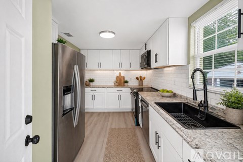 A kitchen with white cabinets and a stainless steel refrigerator.