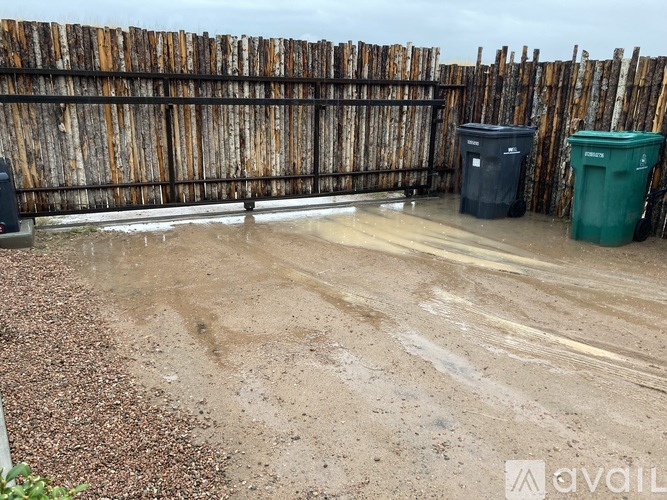 A backyard with a wooden fence and two trash bins.