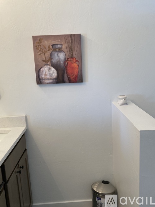 A painting of three vases hangs on a wall above a white counter.