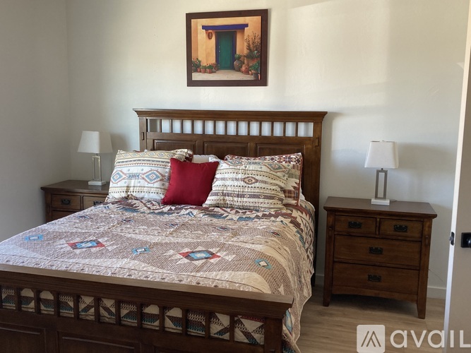 A bedroom with a bed, nightstands, and a painting on the wall.