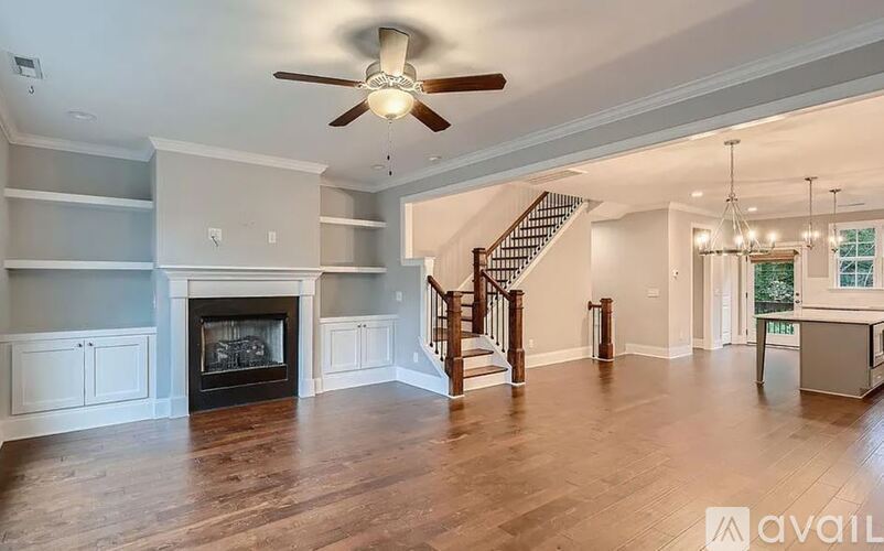A spacious living room with a fireplace and a staircase.