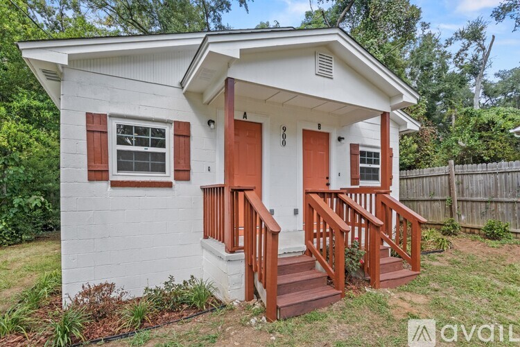 A small white house with a red door and steps leading to the entrance.
