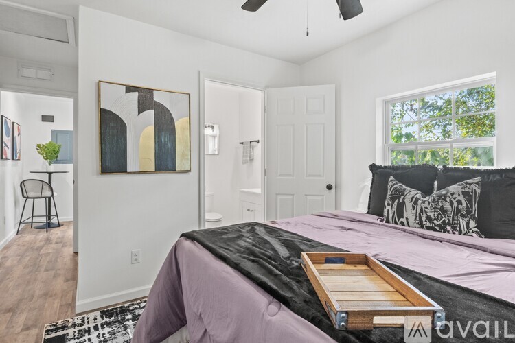 A bedroom with a bed, a ceiling fan, and a painting on the wall.