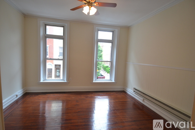 A room with wooden floors and two windows.