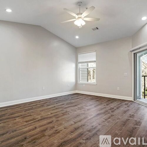 A spacious room with wooden flooring and a ceiling fan.