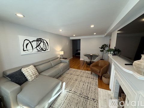 A living room with a grey couch and a painting on the wall.