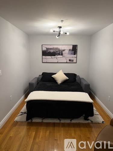 A black and white bedroom with a bed and a framed picture on the wall.