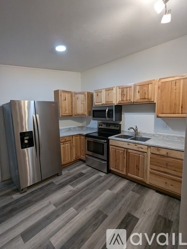 A kitchen with wooden cabinets and a stainless steel refrigerator.