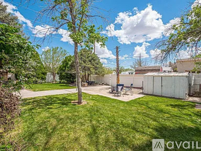 A backyard with a tree, a fence, and a patio area.