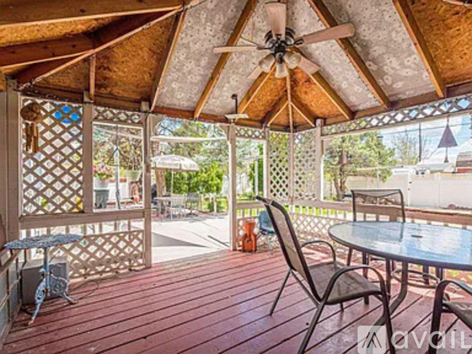 A wooden deck with a table and chairs and a ceiling fan.
