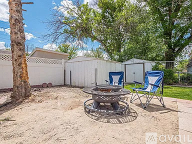 A backyard with a fire pit and two chairs.