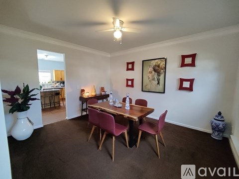 A dining room with a table set for four and a painting on the wall.