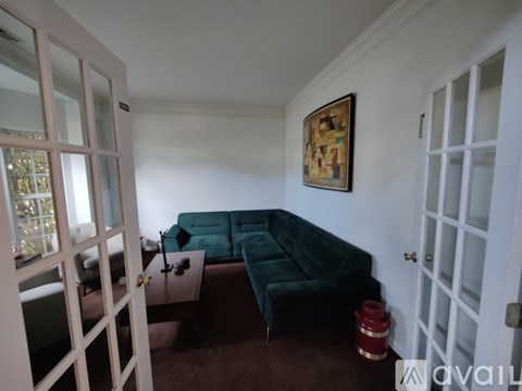 A living room with a green couch and a painting on the wall.