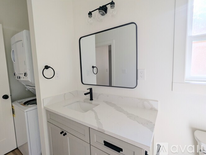A white bathroom with a sink, mirror, and towel rack.