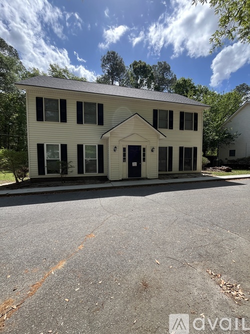 A two-story house with a white facade and black shutters.