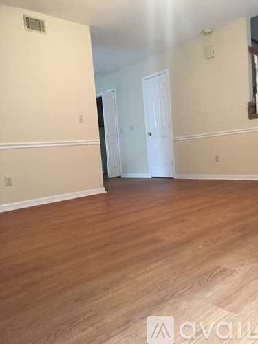 A room with wooden flooring and two white doors.