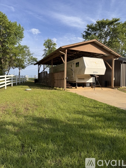A white RV is parked in a wooden shed.