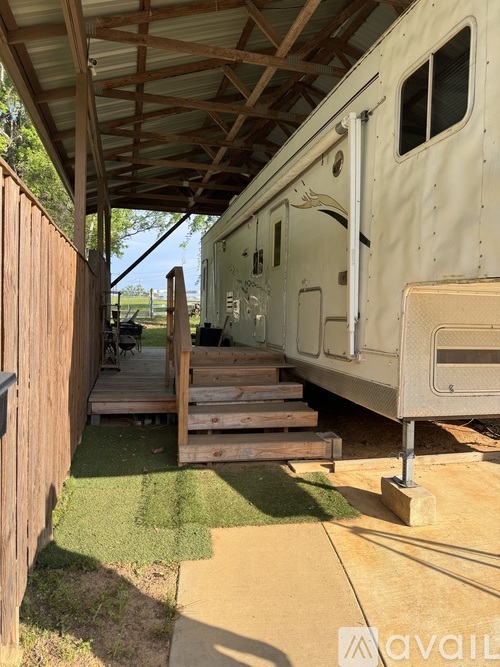 A white RV is parked under a wooden roof.