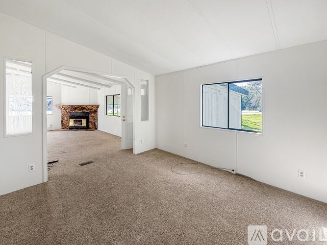 A spacious living room with a fireplace and a view of the backyard through the window.