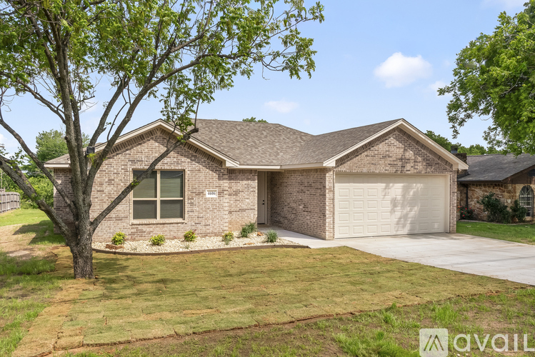A house with a garage and a tree in front of it.