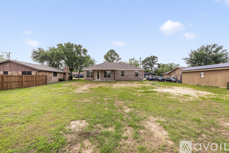 A grassy area with a house and a carport in the background.