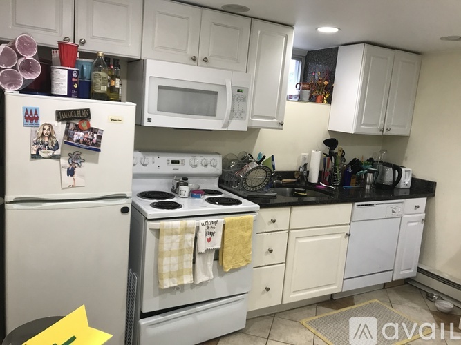 A kitchen with white cabinets and a fridge with magnets.