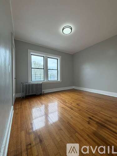 A room with wooden floors and a window with a radiator beneath it.