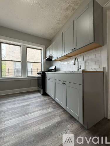 A kitchen with grey cabinets and a white brick backsplash.