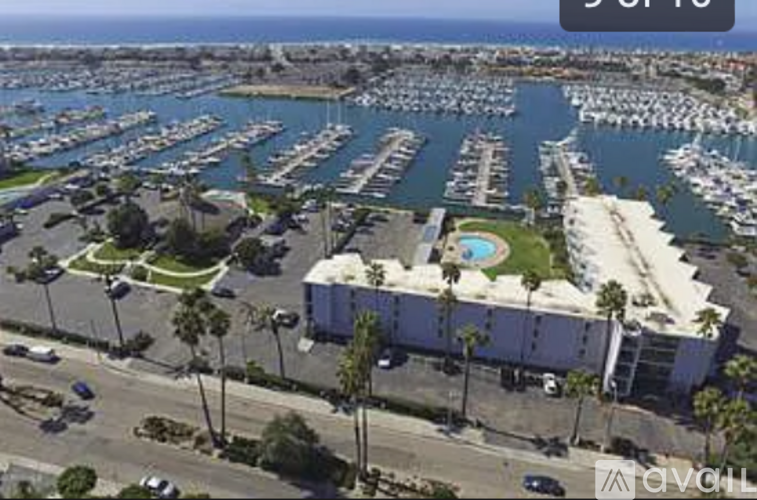A marina with boats and a building with palm trees in front.