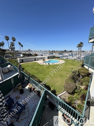 A balcony overlooks a pool and a green lawn.