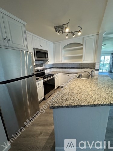 A kitchen with a stainless steel refrigerator and a granite countertop.