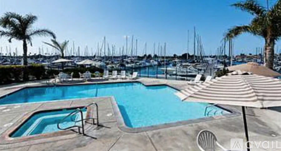 A pool with a hot tub and a view of boats in the background.
