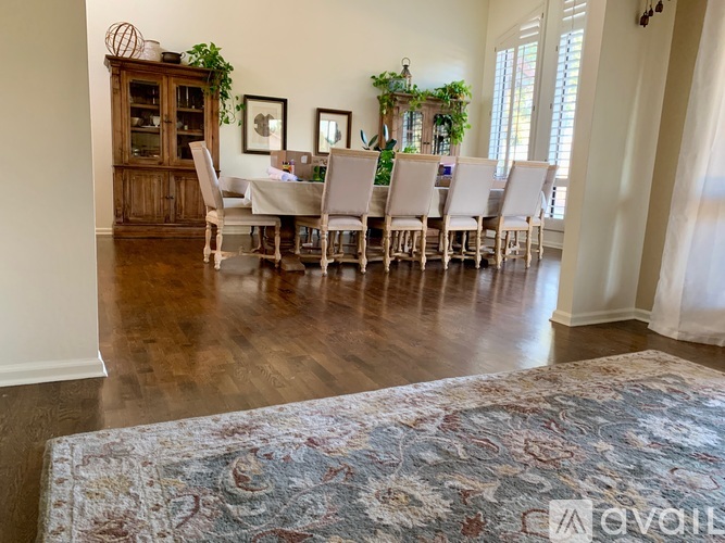 A dining room with a table set for six with a rug in the foreground.