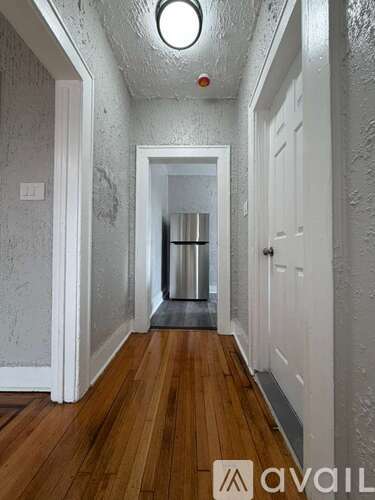 A hallway with wooden floors and white walls.