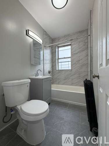 A white toilet is in a bathroom with a marble wall.