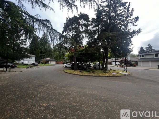A street view with a house and trees in the background.
