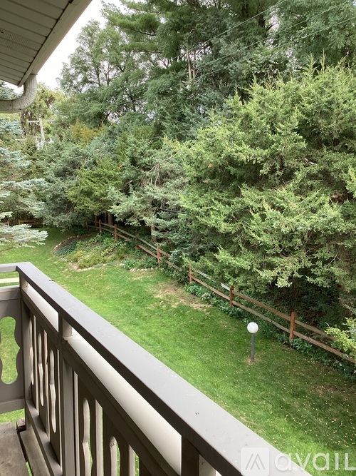 A balcony overlooks a green yard with trees.