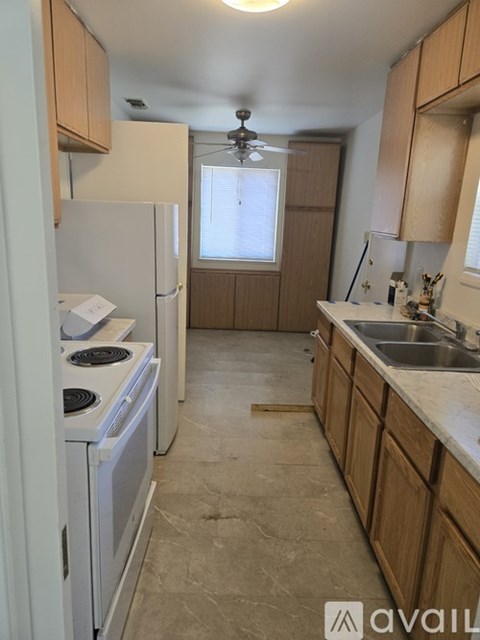 A kitchen with a white refrigerator, a stove, and wooden cabinets.